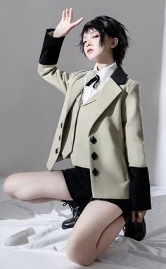 a woman with black hair sitting on top of a bed wearing a suit and tie