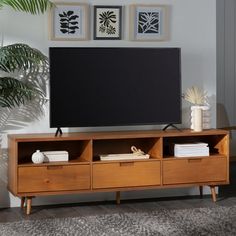 a flat screen tv sitting on top of a wooden entertainment center next to a potted plant