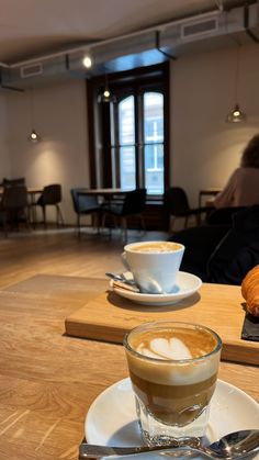 there is a cup of coffee and a croissant on the table