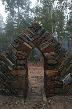 a man standing in front of an arch made out of rocks