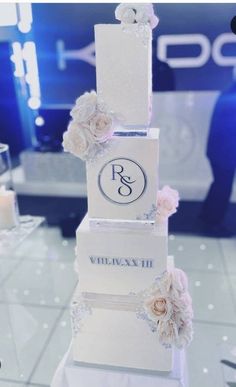 a three tiered wedding cake with flowers on the top and initials on the bottom