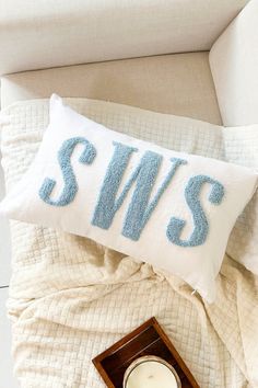 a pillow that says swis on it next to a candle and a small clock