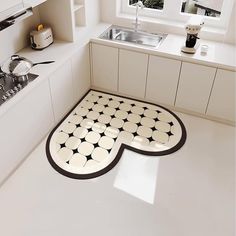 a black and white floor mat in the middle of a kitchen with a sink, stove top and window