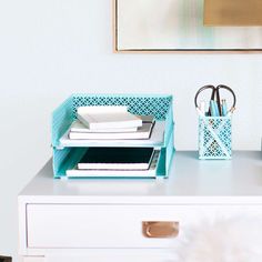 a white desk with a blue container on it and some books in front of the drawer