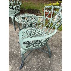 two green metal chairs sitting next to each other on cement ground with plants in the background