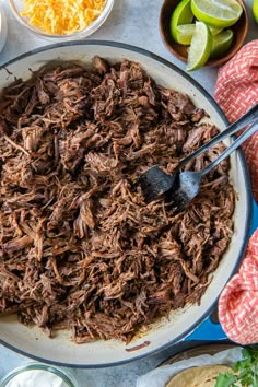 shredded beef in a skillet with limes and sour cream