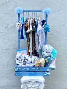 a baby's welcome sign with clothes hanging from it and stuffed animals on the back