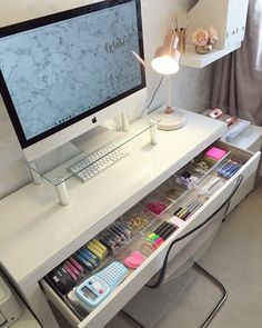 a desk with a computer monitor, keyboard and various other items in the drawer under it