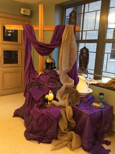 a table with purple cloths and candles on it in front of a large window