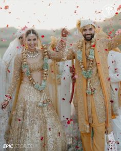 two people dressed in wedding outfits and confetti