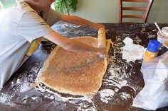 a young boy making bread on top of a table