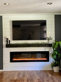 a fireplace with a flat screen tv mounted above it in a living room next to a potted plant