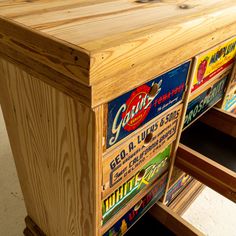 a wooden cabinet with many different types of stickers on the front and bottom drawers