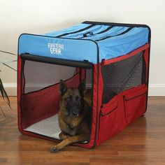 a dog is laying down in a red and blue pet carrier with the door open