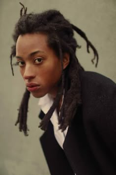 a young man with dreadlocks wearing a suit and tie looking at the camera