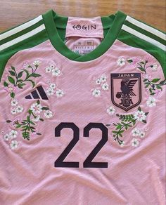 a pink jersey with white flowers on the front and green trim around the neck, along with number 22