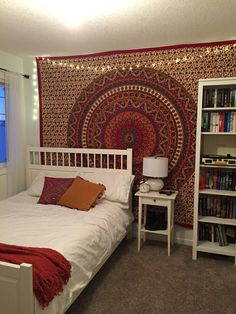 a bedroom with a bed, bookcases and a tapestry on the wall