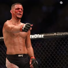 a man with red paint on his face and arm pointing to the side while standing in front of a fence