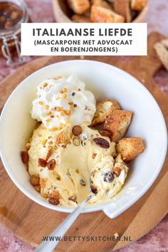 a bowl filled with ice cream on top of a wooden cutting board next to bread