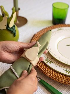 a person is decorating a table with green napkins and place settings on it