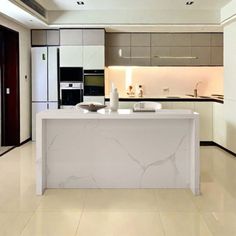 a modern kitchen with marble counter tops and white cabinets, along with an island in the middle