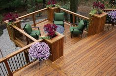 a wooden deck with green chairs and purple flowers