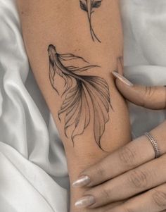 a woman's arm with a tattoo on it that has a goldfish and flowers