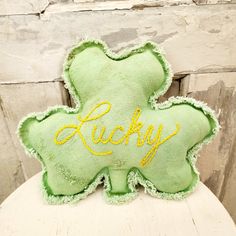 a green stuffed animal with the word lucky written on it's back in gold thread