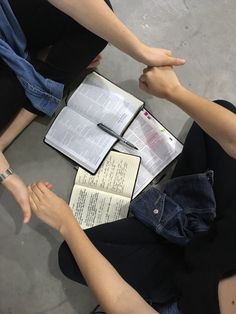 three people sitting on the floor with open books and notebooks in their lap tops