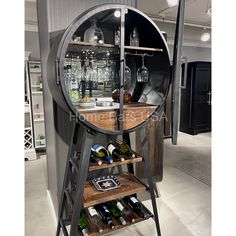 a wine rack with bottles and glasses on it in the middle of an open room