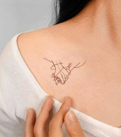 a woman with a tattoo on her shoulder holding the hand of another person's arm