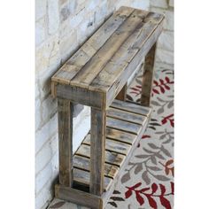 a wooden bench sitting in front of a brick wall next to a red and white rug