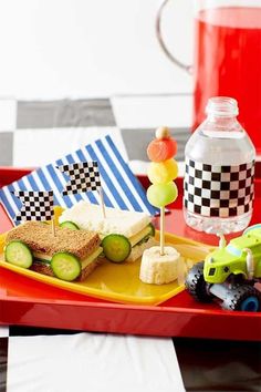 a red tray topped with sandwiches and veggies next to a bottle of water