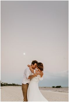 a bride and groom embracing on the beach