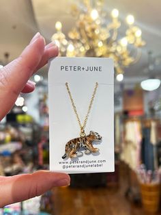 a person holding up a necklace with a dog on it in front of a store