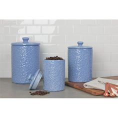 three blue canisters sitting on top of a counter next to a cutting board