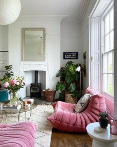 a living room filled with pink furniture and lots of potted plants on top of it