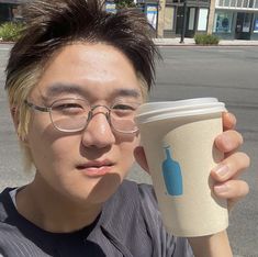 a man with glasses holding up a coffee cup