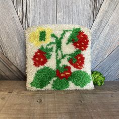 a white square with red and yellow flowers on it sitting on top of a wooden table