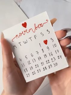 someone is holding up a calendar with hearts on it and the date written in red