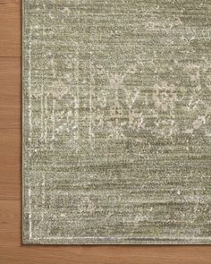 an area rug on top of a wooden floor with white and green designs in the middle