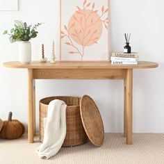 a wooden table sitting next to a white wall with a plant on top of it