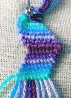 a crocheted keychain with a blue, purple and white stripe on it