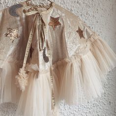 a white dress with gold stars and moon patches on the collar, along with tulle skirt