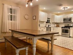 an empty kitchen with white cabinets and wood flooring is seen in this image from the dining room