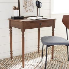 a desk with a chair, lamp and pictures on the wall in front of it