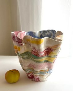 a ceramic vase sitting next to an apple on a table