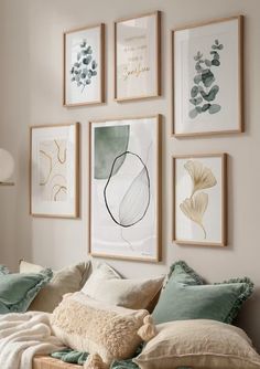 a bed topped with lots of pillows next to framed pictures on the wall above it