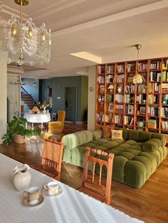 a living room filled with lots of furniture and bookshelves next to a dining table