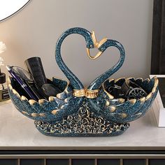 a decorative blue swan shaped container on a table with makeup and other items in it